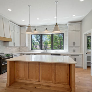 Murray Custom Homes designed kitchen with wood island, white cabinets, black fixtures, and modern lighting.
