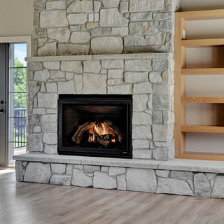 Stone fireplace with gas logs, light wood built-in shelving, glass door to outdoor deck, and light hardwood flooring.