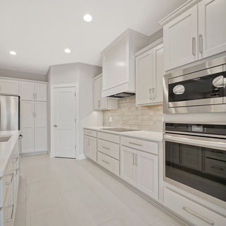 Murray Custom Homes designed bright kitchen with white cabinets, stainless steel appliances, and marble countertops.