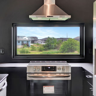 Murray Custom Homes designed kitchen with black walls, stainless steel stove and refrigerator, and large window overlooking greenery.