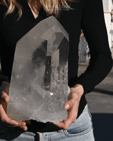 Person holding a large clear quartz crystal point, symbolising clarity, intention, grounding and positive energy.