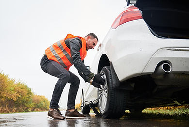emergency-auto-mechanic-changing-flat-tire-road.jpg