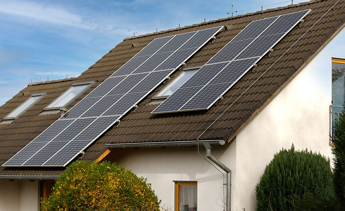 A solar panel installation on a sloped roof, with multiple panels arranged and visible under a clear blue sky.