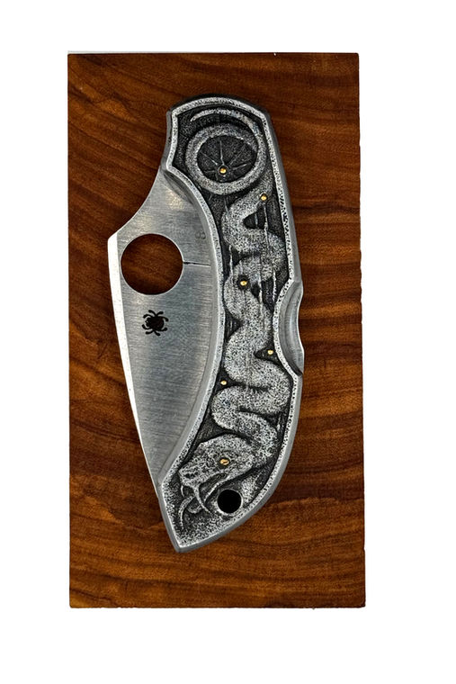 Hand-engraved snake knife displayed on wood