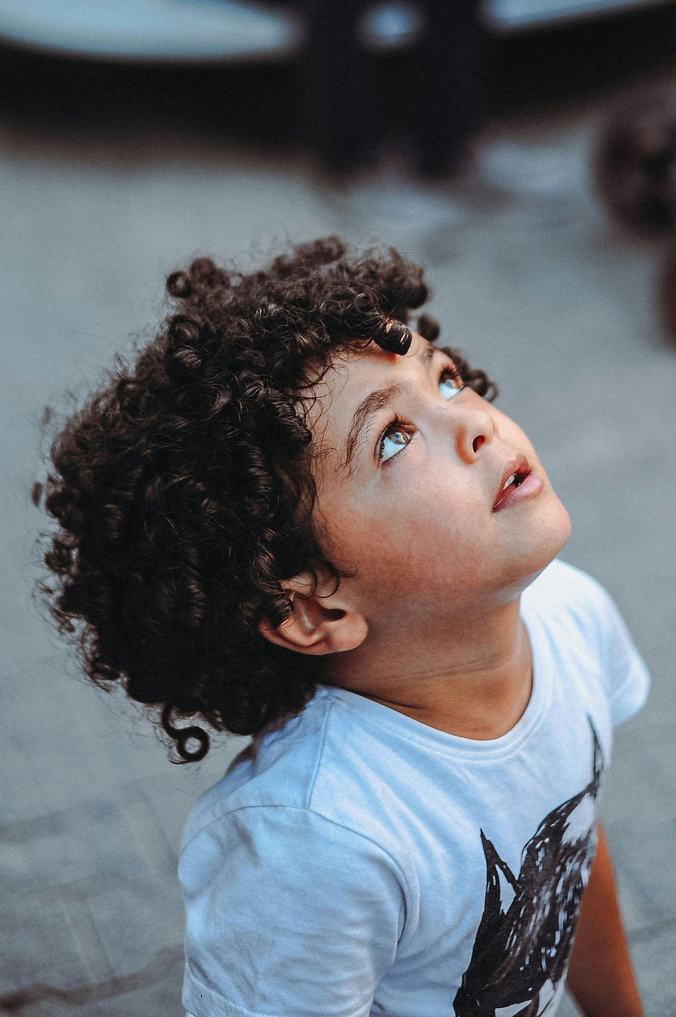 cute little curly-haired boy looking up at the sky