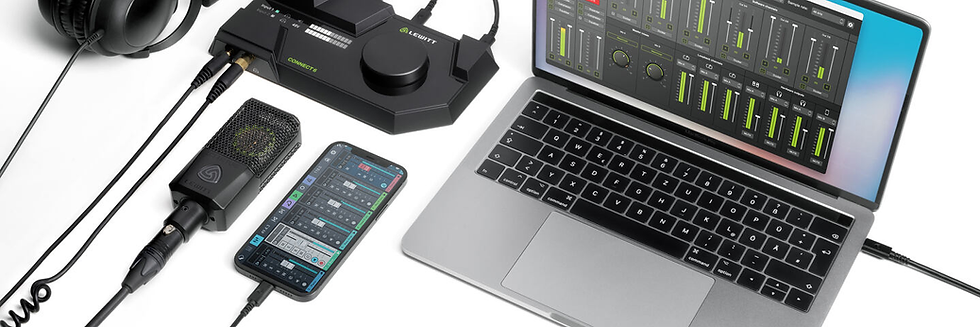 Laptop showing audio mixing software, smartphone with music app, microphone, and headphones on a desk. Black and silver tones.