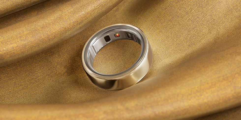 Gold and silver ring with black and red sensors on gold fabric background. Elegant and luxurious setting with a smooth texture.