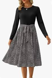 Woman in a black top and patterned skirt, displaying the flow of the dress. White background, no visible text, calm mood.