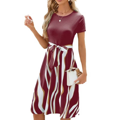 Woman in a burgundy dress with white and gold stripes holds a white handbag. She stands against a plain background, exuding elegance.