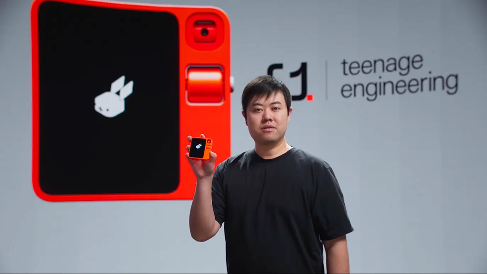 Man in black shirt holding an orange device with a rabbit icon. Large screen and "teenage engineering" text in the background.