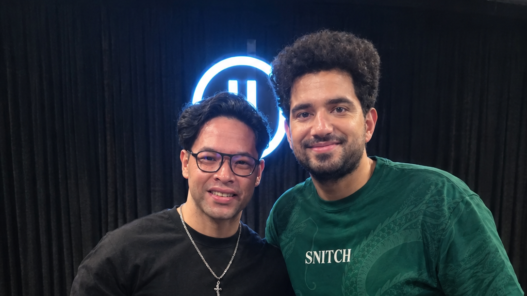 Melofit Emir & Samay Raina pose in front of a neon logo and black curtains, with confetti on the floor; one shirt reads SNITCH.