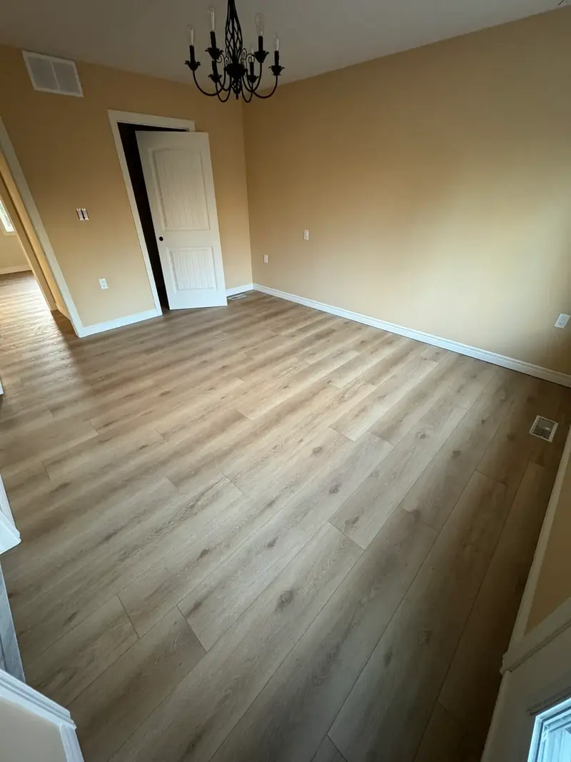 Natural wood-look vinyl flooring installed in a cozy bedroom in Ancaster, with white baseboards and soft lighting.