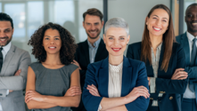 A diverse group of six professional leaders standing together in a modern office environment, all with arms crossed and confident, welcoming smiles. In the context of organizational leadership and conflict resolution, images like this remind us that effective teams are built on the foundation of diverse perspectives and inclusive leadership. 