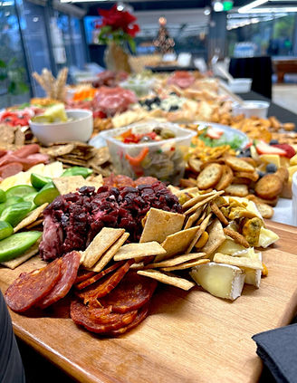 Large charcuterie board with various meats, cheeses, crackers and appetizers On The Roll Catering