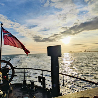 View from the back of the boat, with a flag and sunset
