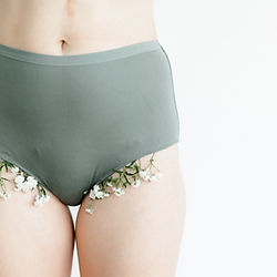 Person wearing green underwear decorated with white flowers against white background
