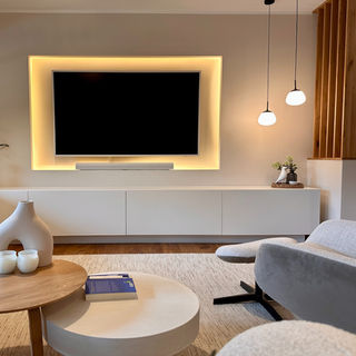 Modernes Wohnzimmer mit hinterleuchteter Rückwand und Pendelleuchten im Japandi Stil modernes Wohnzimmer mit Kamin und Holzpaneelen und einem Unterschrank aus Holz von Detailverliebt - Interior Design Bocholt