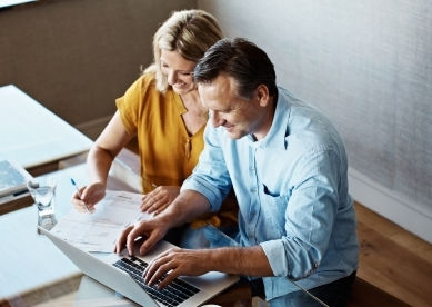Couple reviewing documents and using a laptop together.