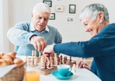 Senior man and woman playing chess together indoors