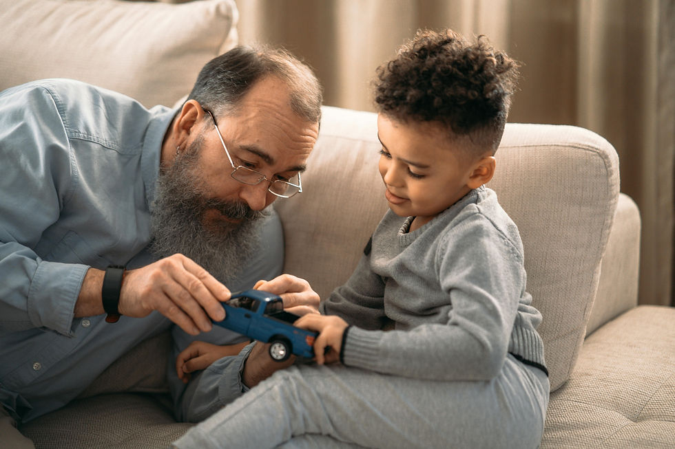 A grandfather helping a young boy with his toy car.