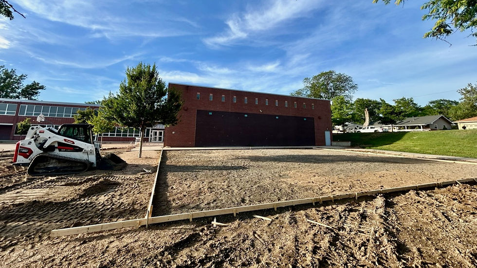 A new playground pad is framed in in front of a brick school building