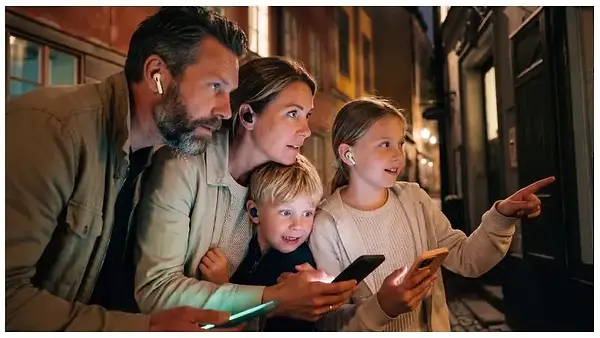 A family enjoying an evening ghost walk in the Old Town using their mobile phone and headphones.