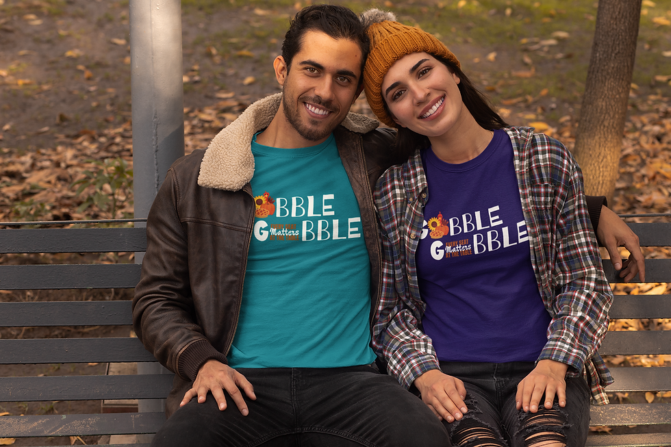 Thumbnail: Couple wearing "Gobble Gobble" T-shirts, sitting on bench outdoors during fall season.