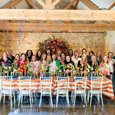 A group of florist gathered behind a table full of flowers.