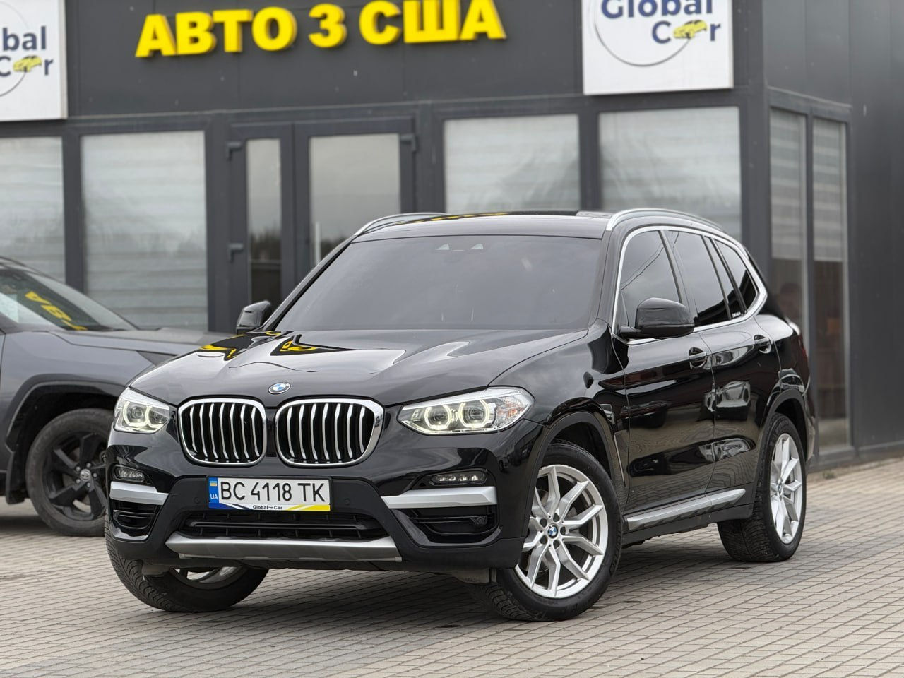 Чорний кросовер 2020 BMW X3 Xdrive30I біля жовтого напису "Авто з США"