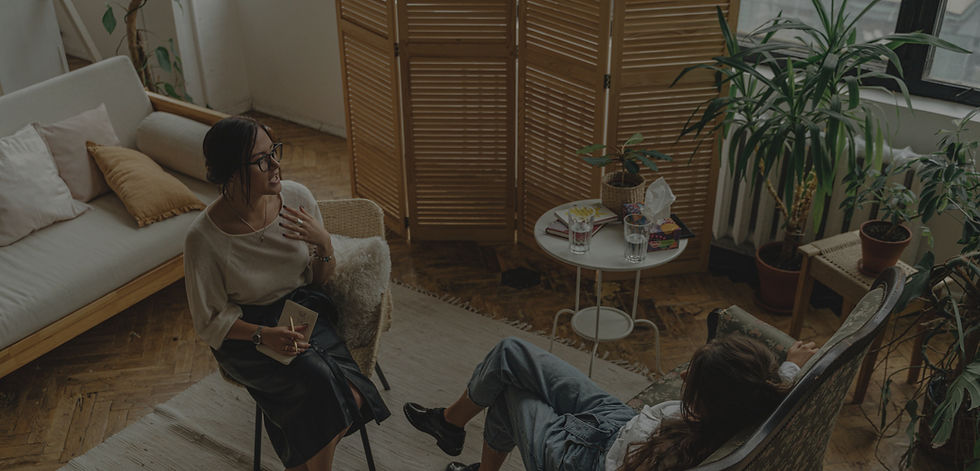 Therapist talking with a young woman client in a cozy, plant-filled psychotherapy office in New York City, representing Boundless Therapy’s warm, culturally responsive counseling space for young adults and professionals.