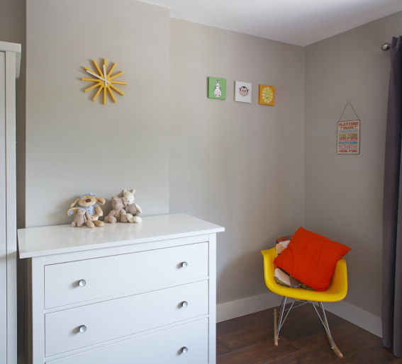 White dresser, yellow chair, sun decor, grey walls, wooden floor, Colorful Nursery.
