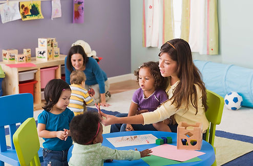 Preschool teachers working with infants and toddlers at a childcare center.