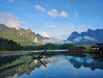 Limestone mountains reflected in calm water at Cheow Lan Lake in Khao Sok