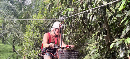 Traveler navigating a narrow aerial rope line high among dense jungle foliage in Khao Sok