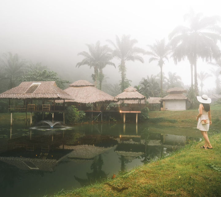 Lakeside raft houses partially hidden by dense white mist during a peaceful Khao Sok morning