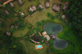 Top-down aerial view of nature bungalows arranged around tropical gardens and a small pond in Khao Sok