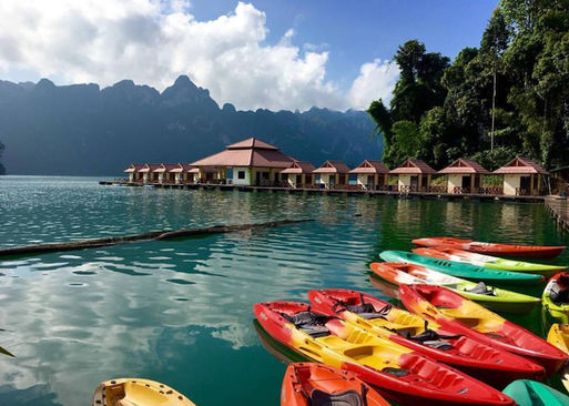 Colorful kayaks beside Saichol floating bungalows with limestone mountains in Khao Sok