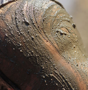 Close-up of female thigh and bikini strap covered in textured black mineral mud for skin d