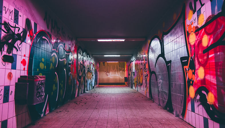 Decorative image of empty tunnel with colourfully graffittied walls.