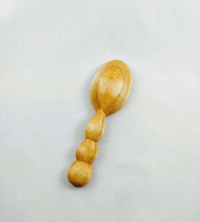 Thumbnail: Back view of small spoon with short handle carved into a row of three semi-spherical shapes.