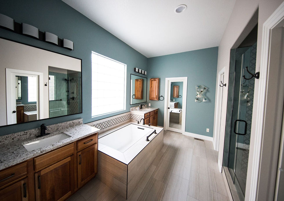 Spacious master bathroom with teal blue accent wall, wood cabinets, granite countertops, and freestanding soaking tub.