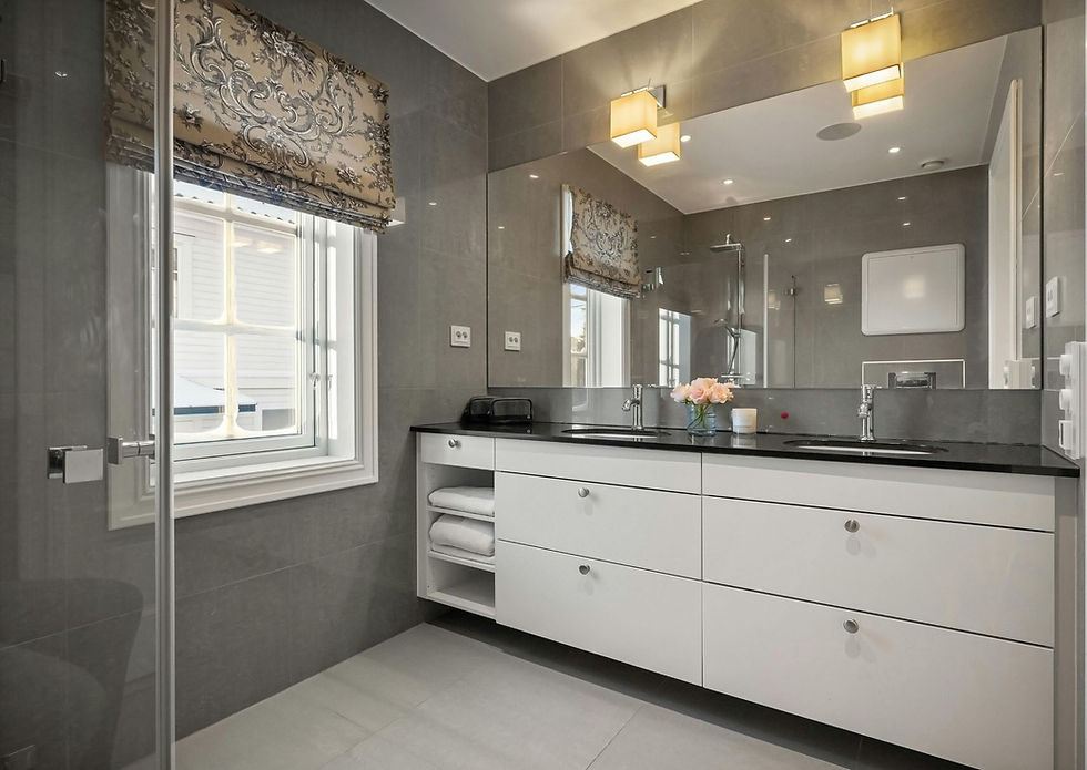 Modern gray tiled bathroom with white floating vanity, black countertop, decorative window treatments, and glass shower.
