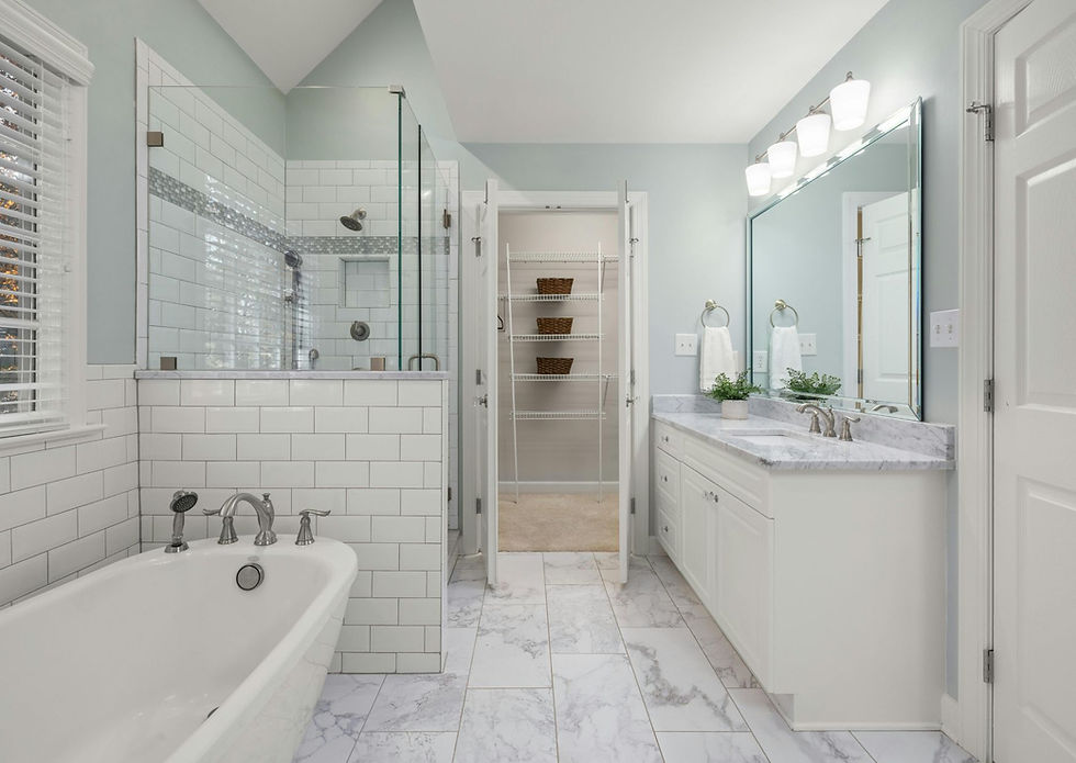 Serene bathroom with soft blue walls, white subway tile shower, marble floors, freestanding tub, and white vanity.