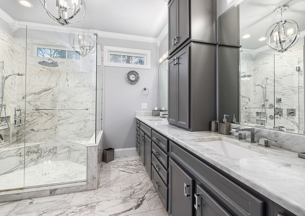 Sophisticated master bathroom with gray marble tile, dark wood cabinetry, glass shower, and crystal chandelier lighting fixtures.