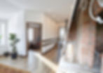 Split view showing completed modern renovation with wood floors beside unfinished brick wall construction area.