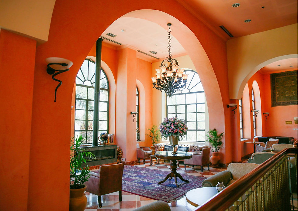 Vibrant terracotta living room with arched doorways, large arched windows, crystal chandelier, and purple oriental rug.