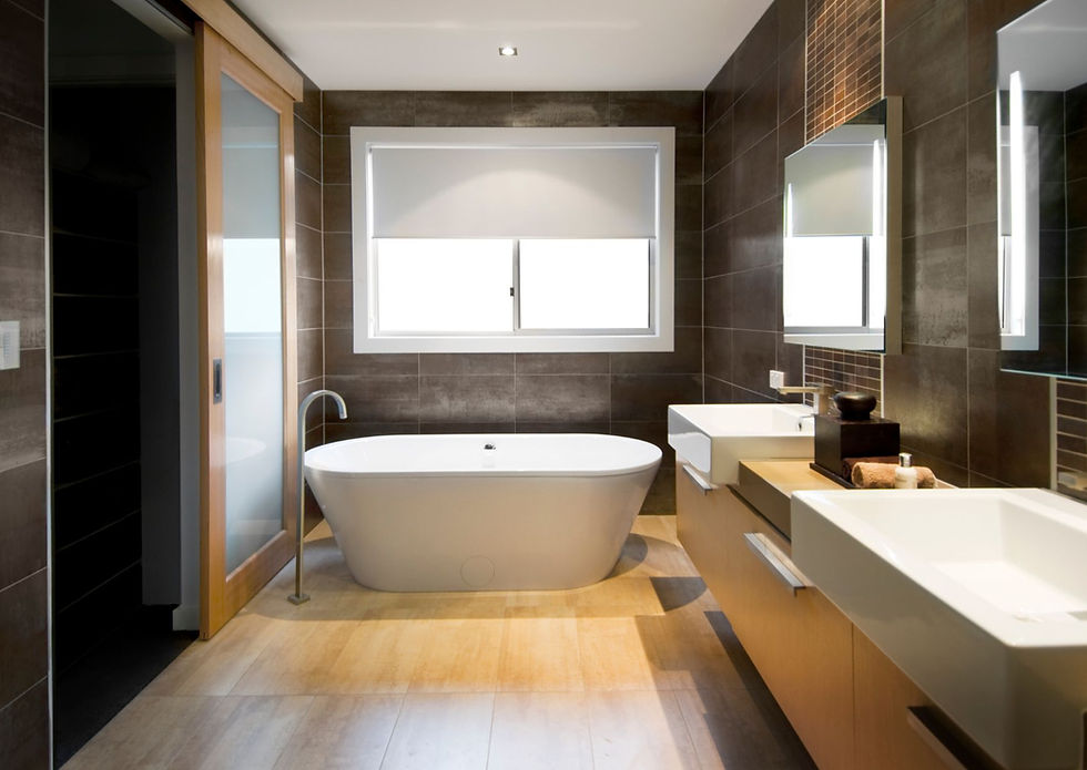 Modern master bathroom with dark brown tile walls, freestanding white tub, floating vanity, and wood floor accents.