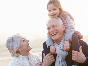 An elderly couple with their granddaughter walking and laughing.