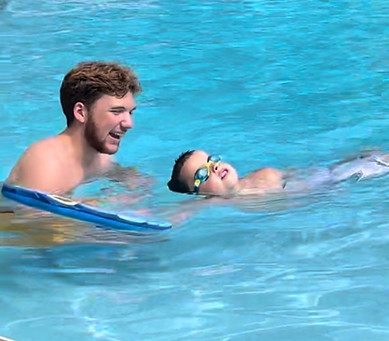 Swimming instructor teaching you boy how to swim