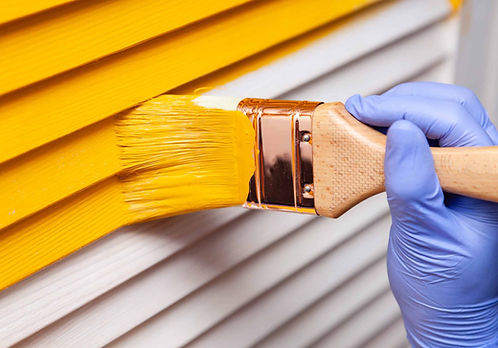 Closeup-female-hand-in-purple-rubber-glove-with-paintbrush-painting-natural-wooden-door-wi